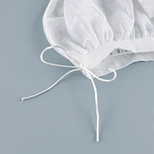 Macro view of the elegant drawstring bow detail on white semi-transparent striped trousers