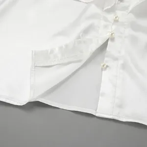 Macro detail shot of white satin blouse with pearl buttons and ruffled placket trim