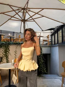 Elegant pale yellow satin peplum camisole top for women's summer fashion outfit.
