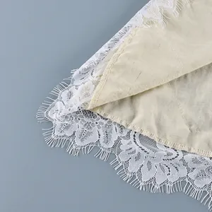 Macro detail view of delicate white eyelash lace hem on a French style beige blouse