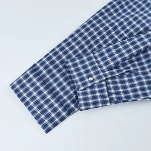 Close-up detail of a blue and white checkered cotton shirt cuff with a silver metal button