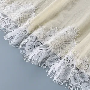 Detailed close-up showing the intricate white eyelash lace trim on a cream wrap blouse