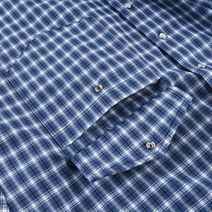 Detailed macro shot of a chest pocket and snap button on a blue plaid cotton shirt