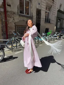 Close-up of a pink elegant coat featuring a long white fringed decorative belt.