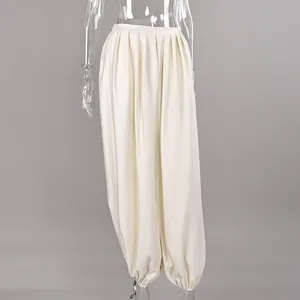 Detail of cream satin lantern pants featuring waist pleats and elastic ankle cuffs