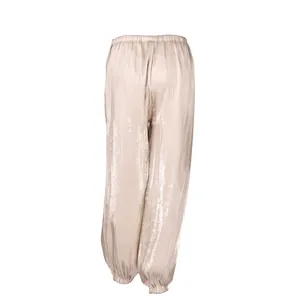 Detailed view of champagne loose harem pants featuring a shimmery metallic texture