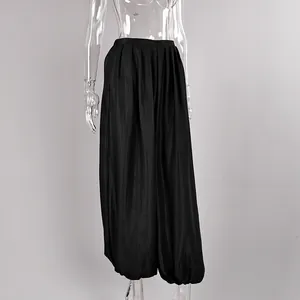 Close-up detail of black satin lantern pants featuring elegant draped fabric and pleats