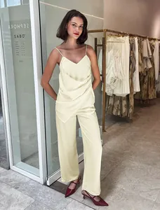 Full view of women's chic cream satin camisole and straight trousers set in a boutique