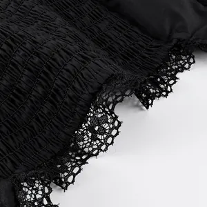 Nahaufnahme der schwarzen gesmokten Textur mit zartem floralem Spitzenbesatz-Detail