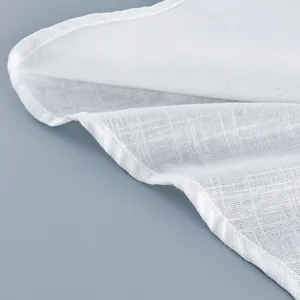 Close-up of white linen fabric texture and hem stitching on a summer camisole dress.