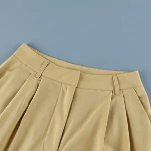 Close-up of the pleated waistband and belt loops on khaki cotton linen trousers.