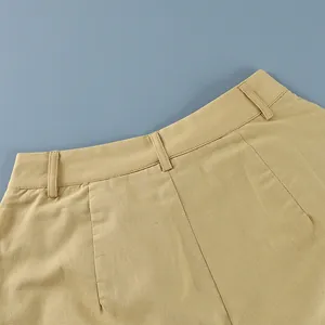 Detail shot of khaki cotton linen trousers waist showing belt loops and texture.