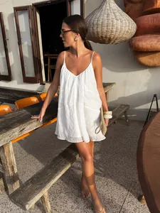 White V-neck camisole mini dress shown in a relaxed sunny outdoor resort cafe setting