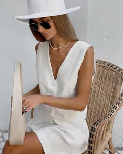 Close-up of a white linen vest and shorts set styled with a straw chair