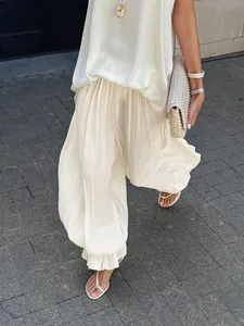 Detailopname van een crème geplooide ballonbroek met een elegante stoffen textuur.