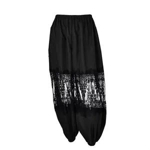 Vista dettagliata di pantaloni neri larghi con pizzo floreale ed elastico alle caviglie.