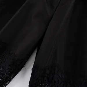 Dettaglio ravvicinato di pantaloni neri larghi con raffinato bordo in pizzo sul fondo