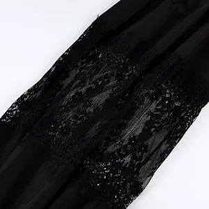 Dettaglio ravvicinato del pizzo floreale sui pantaloni neri larghi stile patchwork
