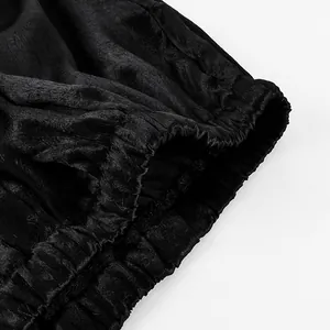 Dettaglio del tessuto nero a trama stropicciata sulla cintura dei pantaloni donna