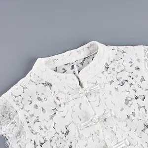 Vue détaillée d'un haut sans manches en dentelle florale blanche avec col officier et boutons.