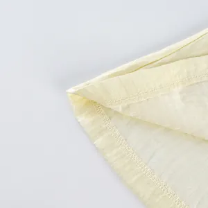 Detailaufnahme des professionell genähten Saums und der Leinentextur der gelben Weste