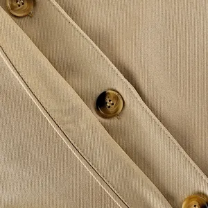 Close-up of khaki trench coat fabric texture with elegant tortoiseshell buttons detail