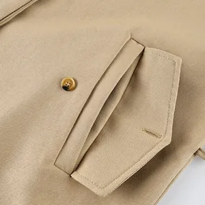 Close-up view of khaki trench coat pocket featuring button and quality stitching
