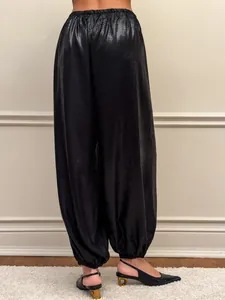 Dettaglio del pantalone nero lucido morbido con vita elastica e fondo gamba a costine