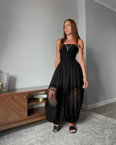 Donna elegante con top a fascia nero e pantaloni harem larghi con inserti in pizzo.