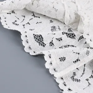 Gros plan sur un tissu de dentelle blanche délicate aux motifs de broderie fleuris.