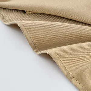 Close-up detail of beige suede-like fabric texture and stitching on a trench coat