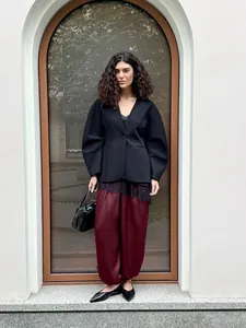 Dettaglio dei pantaloni larghi bordeaux abbinati a un blazer nero strutturato.
