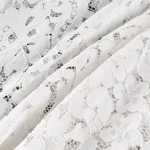 Vue macro détaillée montrant la texture complexe du tissu en dentelle florale blanche du vêtement