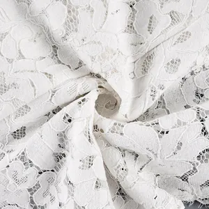 Vue macro montrant le motif floral complexe du détail du tissu en dentelle blanche.