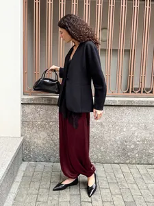 Dettaglio dei pantaloni larghi bordeaux eleganti abbinati a un blazer nero classico