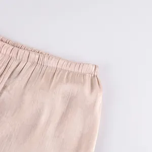 Close-up of elastic waistband on champagne satin lantern pants showing fabric texture.