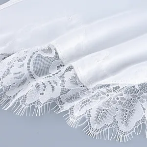 Close-up detail of white satin fabric with intricate floral eyelash lace trim for women.