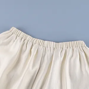 Detail macro view of the elasticated waistband on elegant cream satin fabric trousers