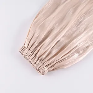 Close-up of the elasticized cuff and textured satin fabric on beige lantern pants.