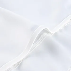 Close-up detail of high-quality white fabric texture and overlock stitching on suit.