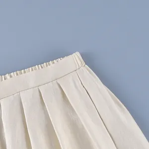 Detailed close-up showing elastic waistband and elegant pleats on cream satin lantern pants