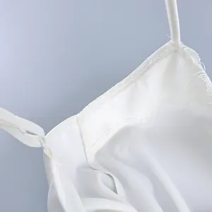 Close-up detail of a white camisole neckline featuring delicate lace trim and thin straps