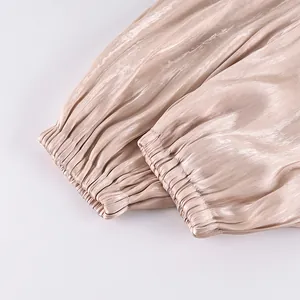 Close-up detail of elastic pleated cuffs on high-shine satin lantern trousers for women