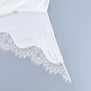 Close-up macro detail of the delicate white eyelash lace trim on a stylish summer vest hem.