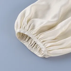 Close-up of elasticated cuff on cream satin lantern pants showing high-quality texture