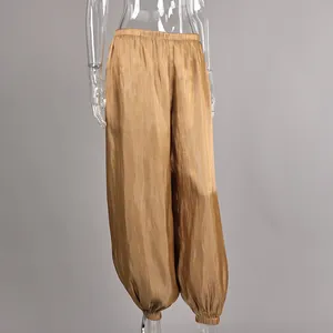 Detailed view of shimmering gold-tone loose lantern pants with elastic waist and ankle cuffs