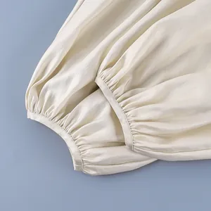 Detail showing elasticized cuffs on elegant cream satin lantern pants for women.