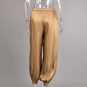Rear view of stylish shiny gold satin lantern pants displayed on a transparent mannequin.