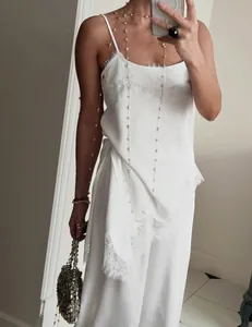 Detailed view of white lace-trimmed camisole and matching wide-leg trousers set