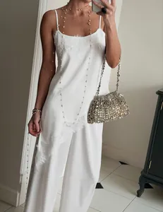 Close-up detail of a white lace-trimmed camisole and matching silk-like wide-leg trousers